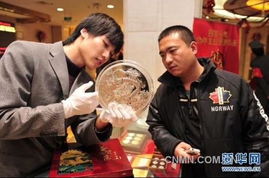 12月21日，工作人員向顧客介紹一款5公斤重的壬辰賀歲紀(jì)念大銀章，其正面的“金龍降喜”圖案，寓意對龍年萬事亨通的美好祝福。