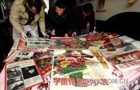 3月1日，房冠龍（中）在家中整理關(guān)于雷鋒的宣傳海報。
