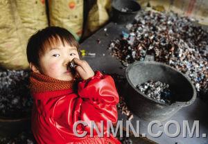 個小朋友在臺州市路橋區(qū)峰江街道一家拆解小作坊內(nèi)玩分揀出來的金屬。